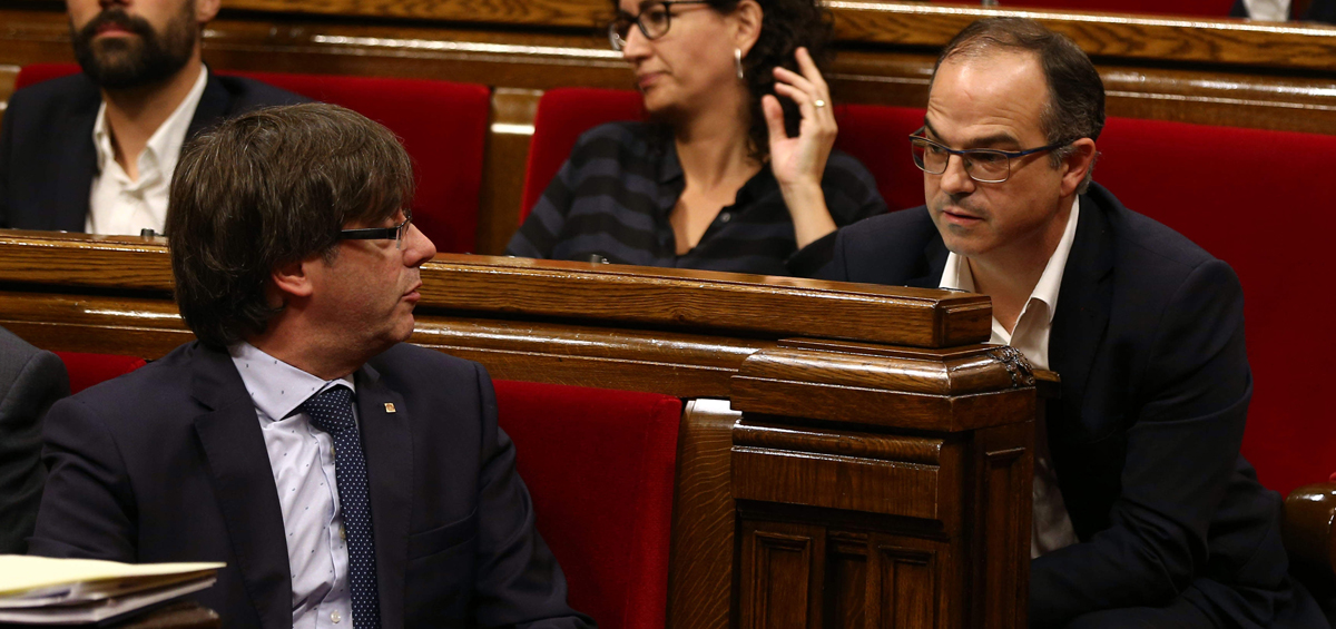 El presidente de la Generalitat, Carles Puigdemont, conversa con Jordi Turull (d).