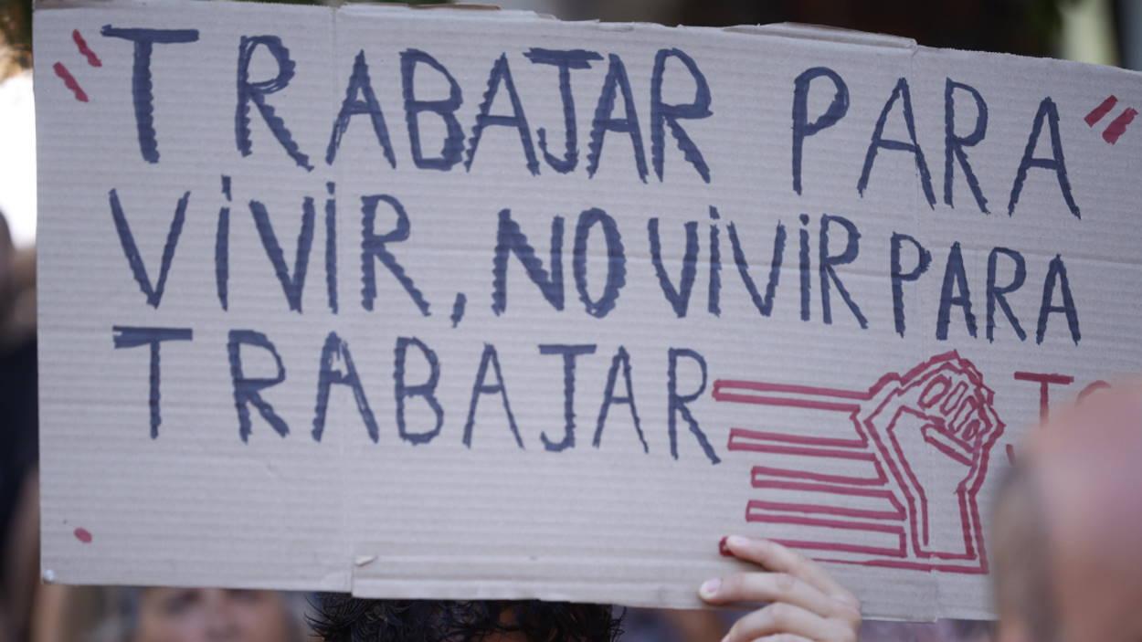 Una persona sostiene una pancarta durante una concentración a favor de la reducción de la jornada laboral. EP.