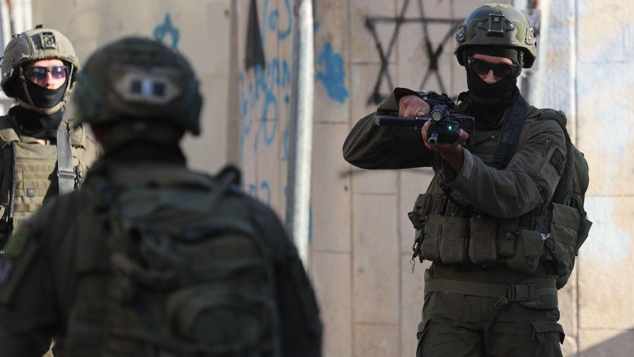 Una familia palestina permanece dentro de su vehículo tras ser detenido durante una incursión de colonos en la Ciudad Vieja de Hebrón, mientras las fuerzas israelíes aseguran la zona. EP.