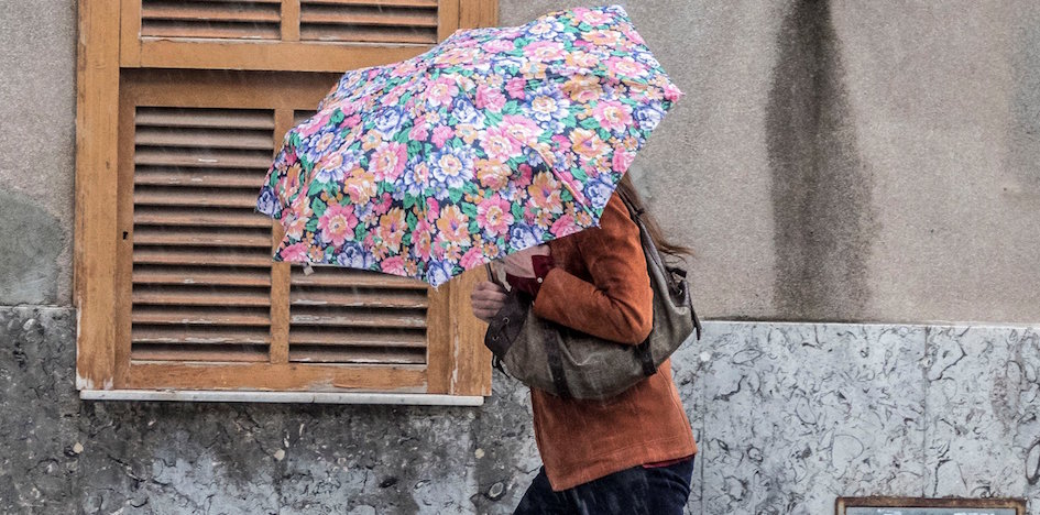 Una mujer camina bajo la lluvia por una calle de Palma de Mallorca. Una mujer camina bajo la lluvia por una calle de Palma de Mallorca.