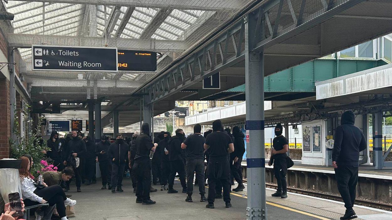 Manifestantes vestidos de negro y enmascarados contra la inmigración ilegal se congregan en la estación de tren de Dover Priory tras bloquear carreteras en Dover. EP.
