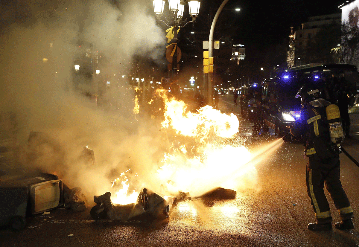 Miembros del cuerpo de bomberos sofocan las llamas de los contenedores de basura incendiados en el Paseo de Gracia de Barcelona, tras la manifestación convocada en los alrededores de la Delegación del Gobierno de Barcelona.