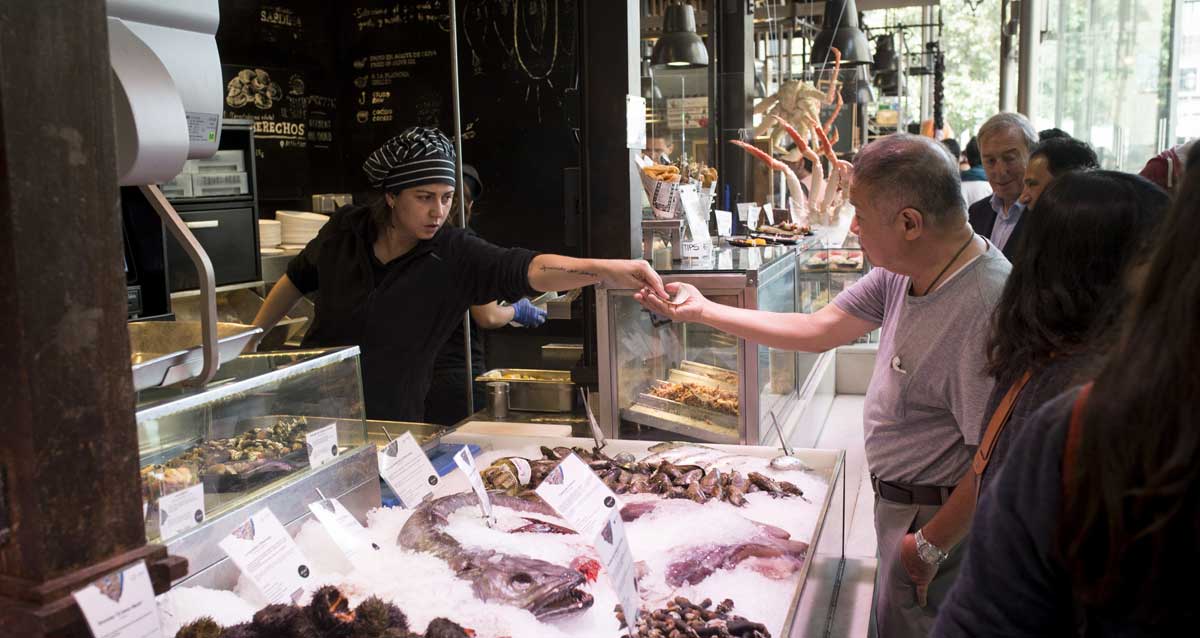 Un turista asiático compra pescado en uno de los puestos del Mercado de San Miguel de Madrid. 