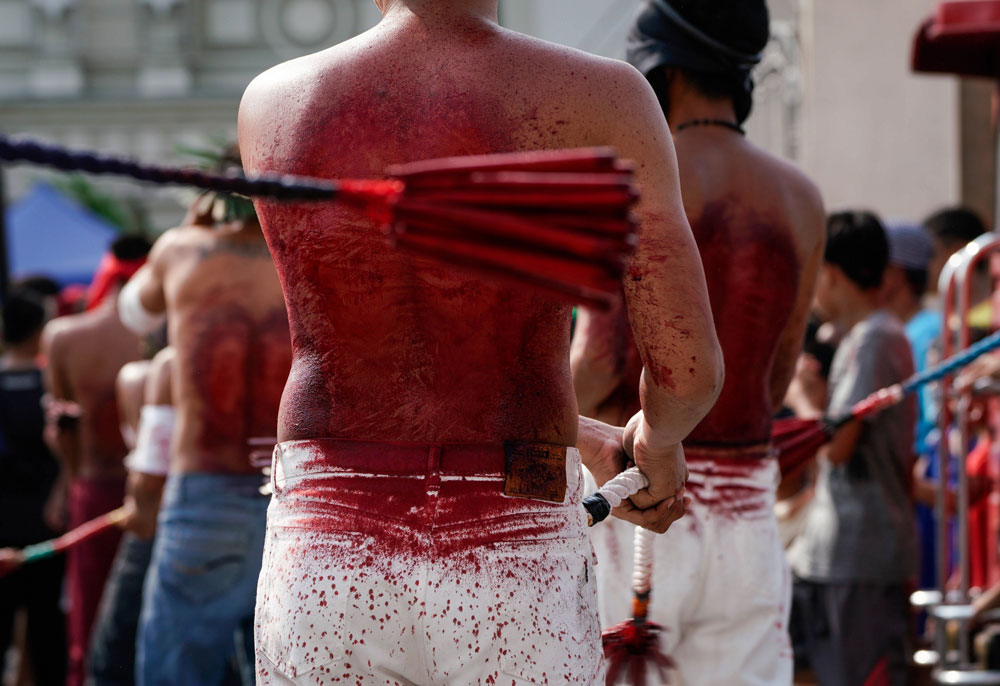 Penitentes se fustigan con el rostro cubierto durante las celebraciones del Jueves Santo en San Pedro Cutud (Filipinas). 