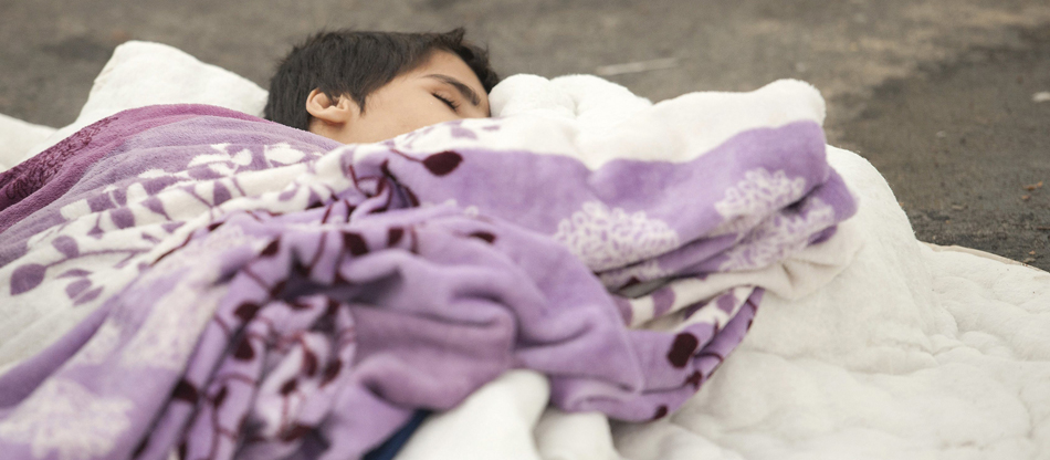 Un niño duerme en el suelo de una calle