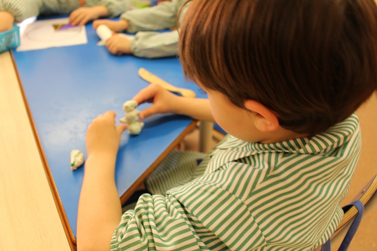 Un niño juega con plastilina en el colegio.