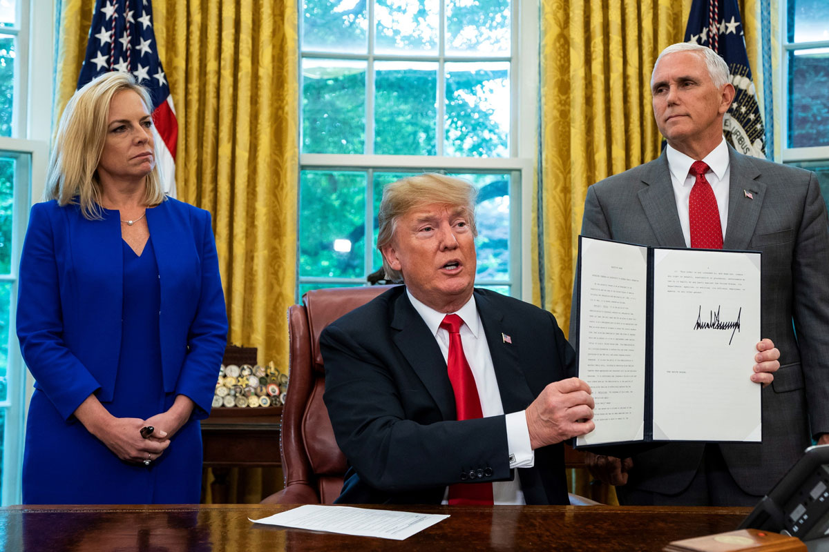 El presidente estadounidense, Donald Trump (c), rodeado por la secretaria de Seguridad Nacional Kirstjen Nielsen (i) y el vicepresidente Mike Pence (d), muestra la orden ejecutiva para detener la separación de los niños inmigrantes de sus padres 