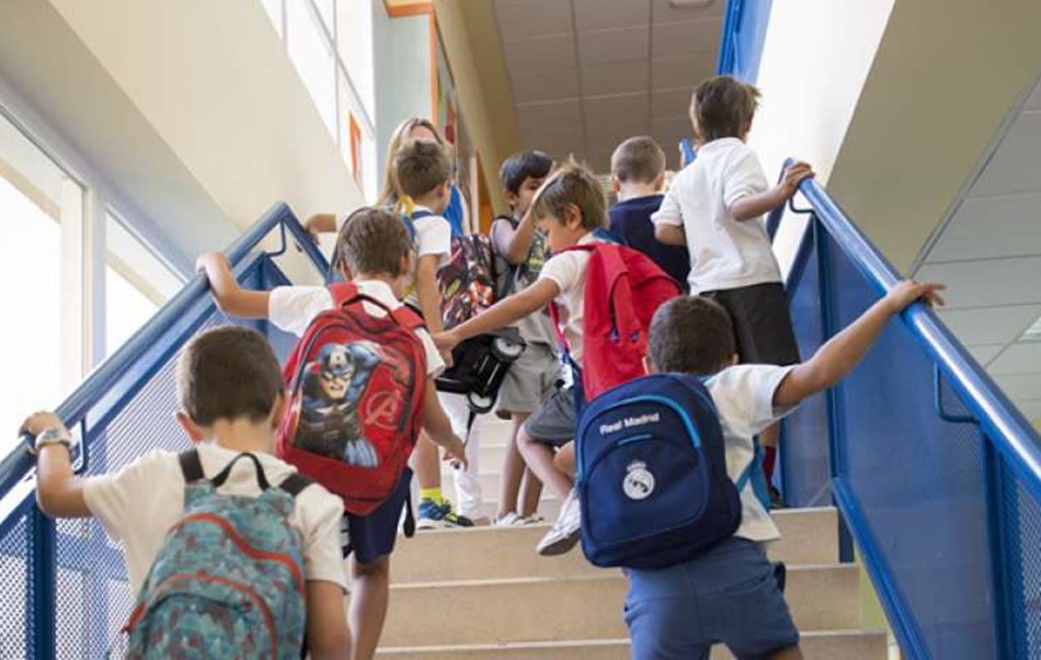Un  grupo de niños suben unas escaleras de un colegio