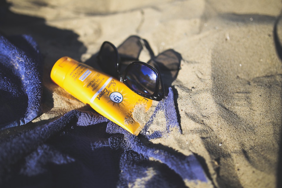 Una toalla, unas gafas y una crema solar, en una playa.