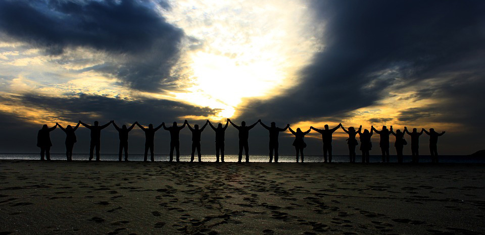 Varias personas dándose la mano en la playa 