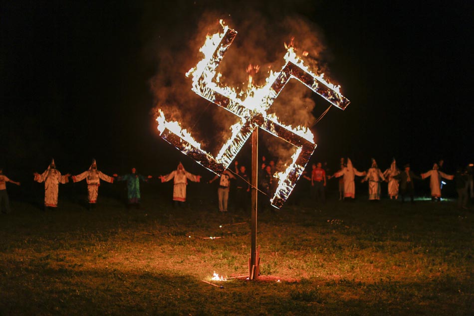 Miembros del movimiento Ku Klux Klan (KKK), mientras queman una esvástica en Temple, Georgia (Estados Unidos), el 23 de abril de 2016.