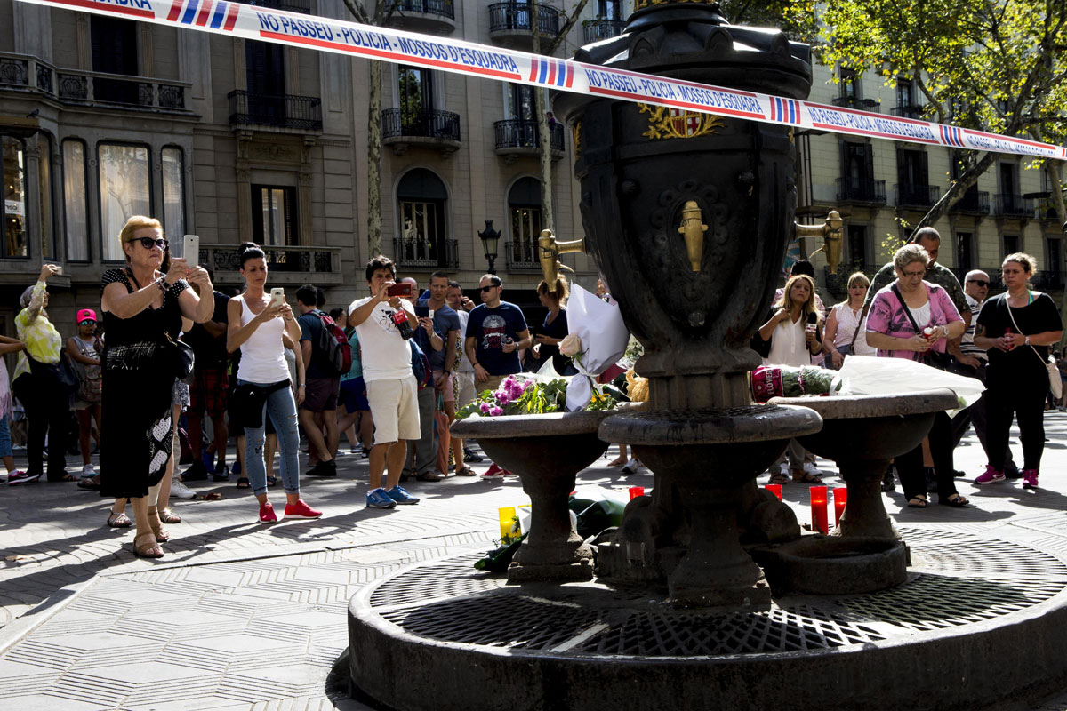 Varias personas fotografían la fuente de Canaletas, en las Ramblas de Barcelona, en la que se han depositado velas y flores después del atentado. 