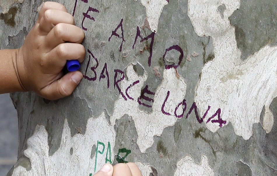 Un niño muestra sus condolencias con un mensaje escrito en un árbol de Las Ramblas de Barcelon