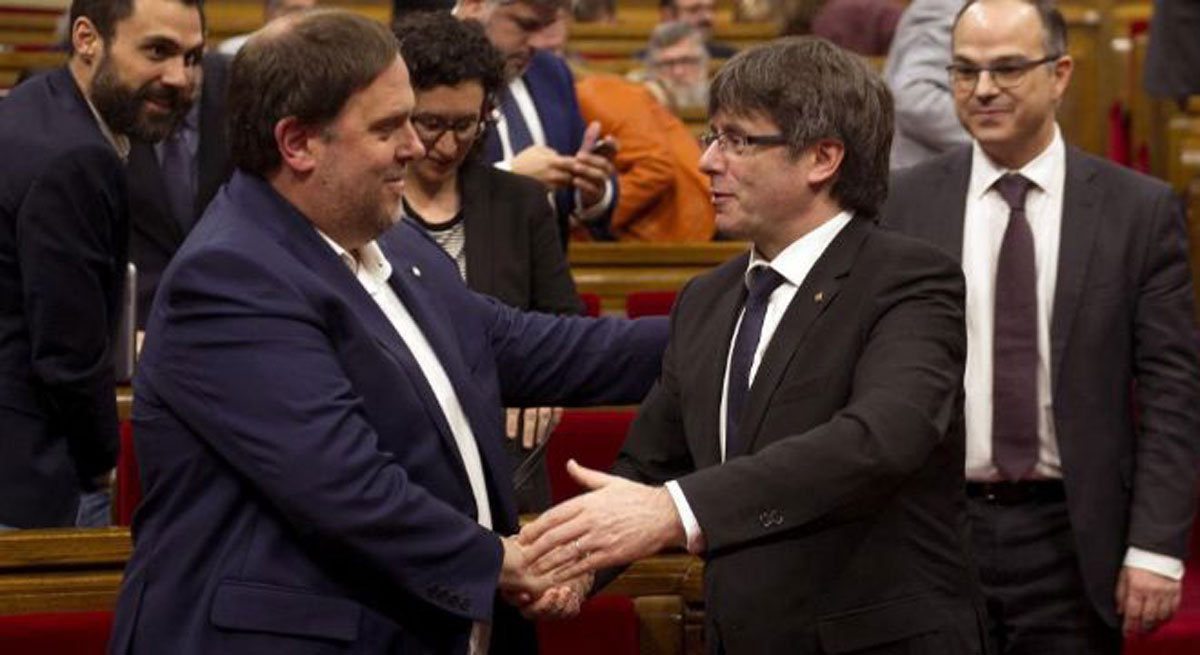 Oriol Junqueras y Carles Puigdemont se dan la mano en el Parlament.