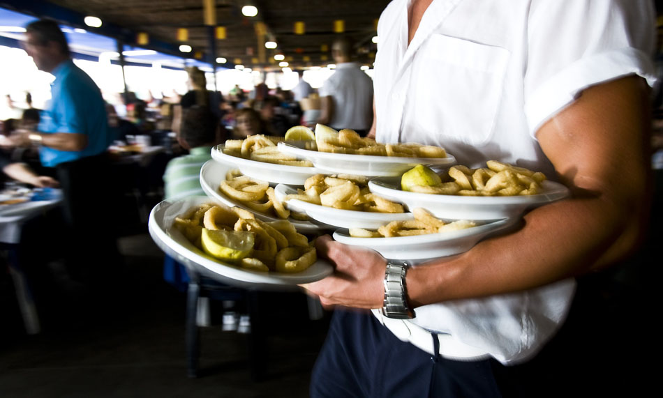Un camarero porta varios platos en un chiringuito de Málaga. 