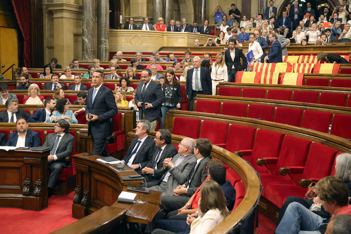 Los diputados de Cs, PSC y PPC abandonan sus escaños en el Parlament, dejando banderas de España y de Cataluña para no votar la ley del referéndum. 