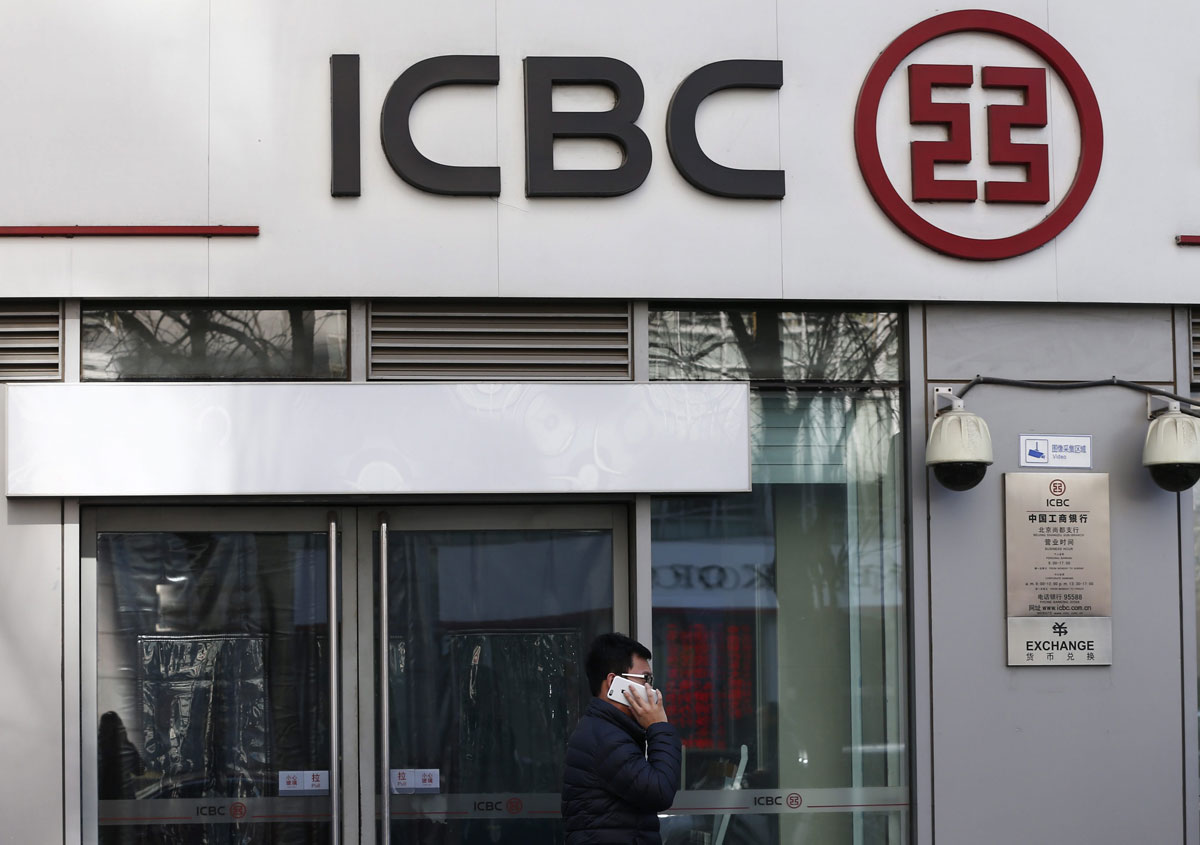 Un viandante utiliza su iPhone mientras pasa delante de una sucursal del banco Industrial and Commercial Bank of China (ICBC)