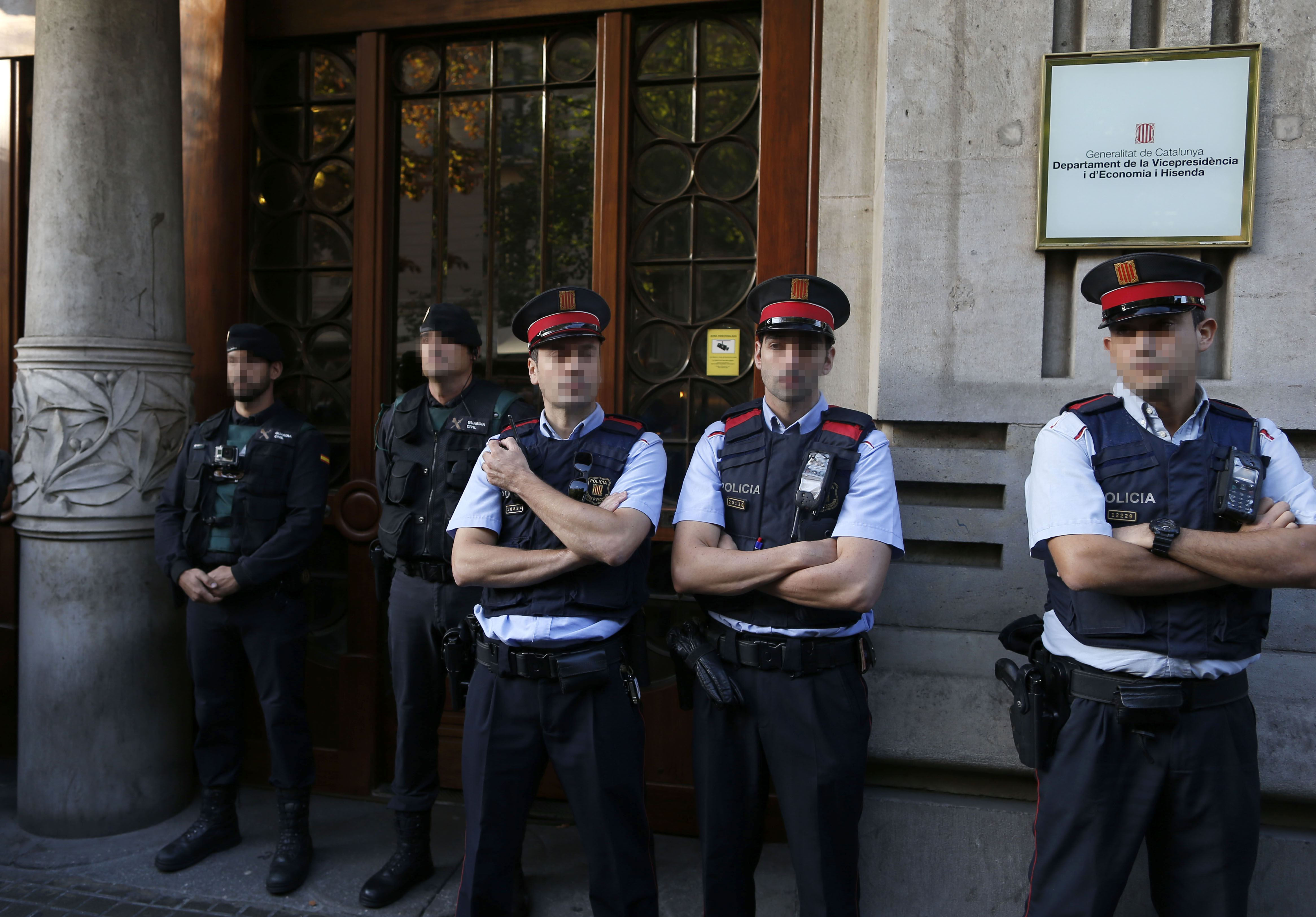 Agentes de la Guardia Civil y de los Mossos d'Esquadra en la puerta de la consellería de Economía de la Generalitat, cuyo titular es Oriol Junqueras, donde agentes del instituto armado se han personado esta mañana en busca de documentación relacionada con