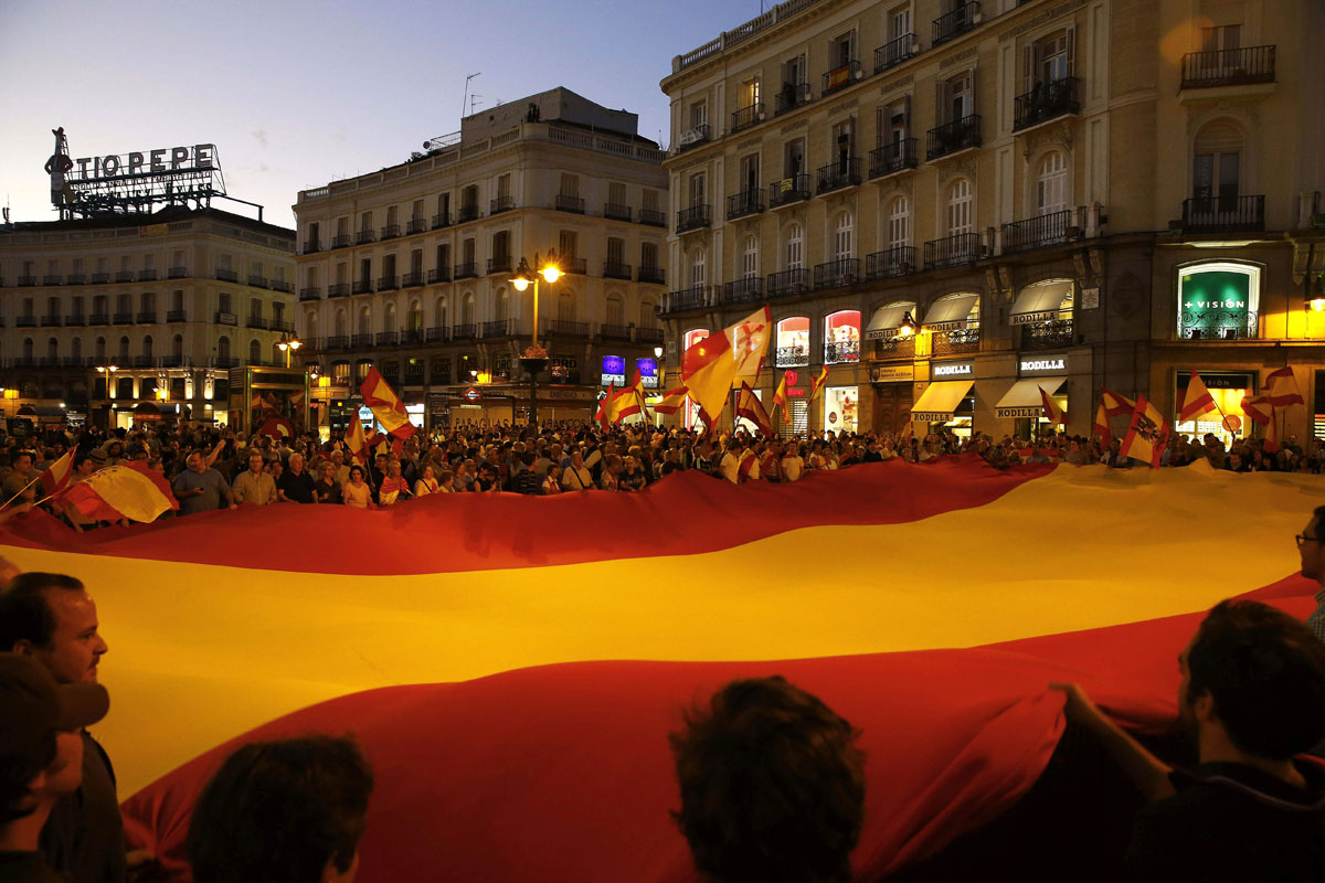 Un grupo de personas desplegando una gran bandera de España en la Puerta del Sol de Madrid