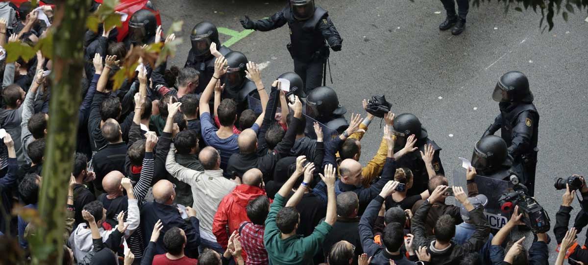 Agentes antidisturbios de la Policía Nacional forman un cordón de seguridad en los alrededores del colegio Ramón Llull de Barcelona. 