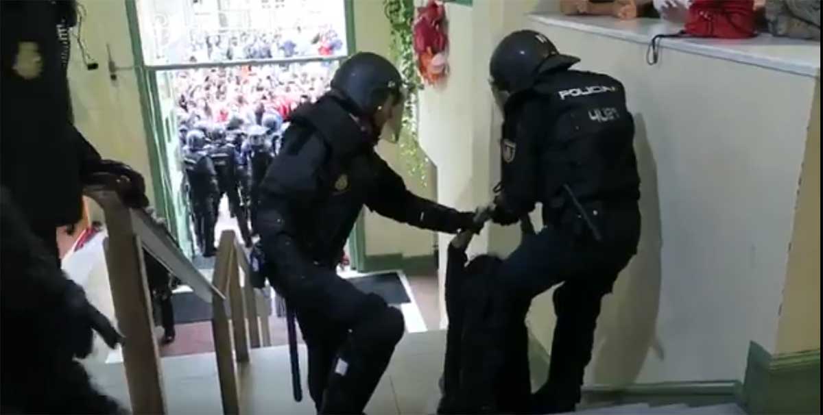 Un agente antidisturbios arrastrando a la mujer que aseguró le habían roto los dedos de la mano