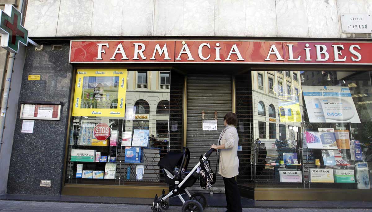 Una mujer contempla la fachada de una farmacia. 