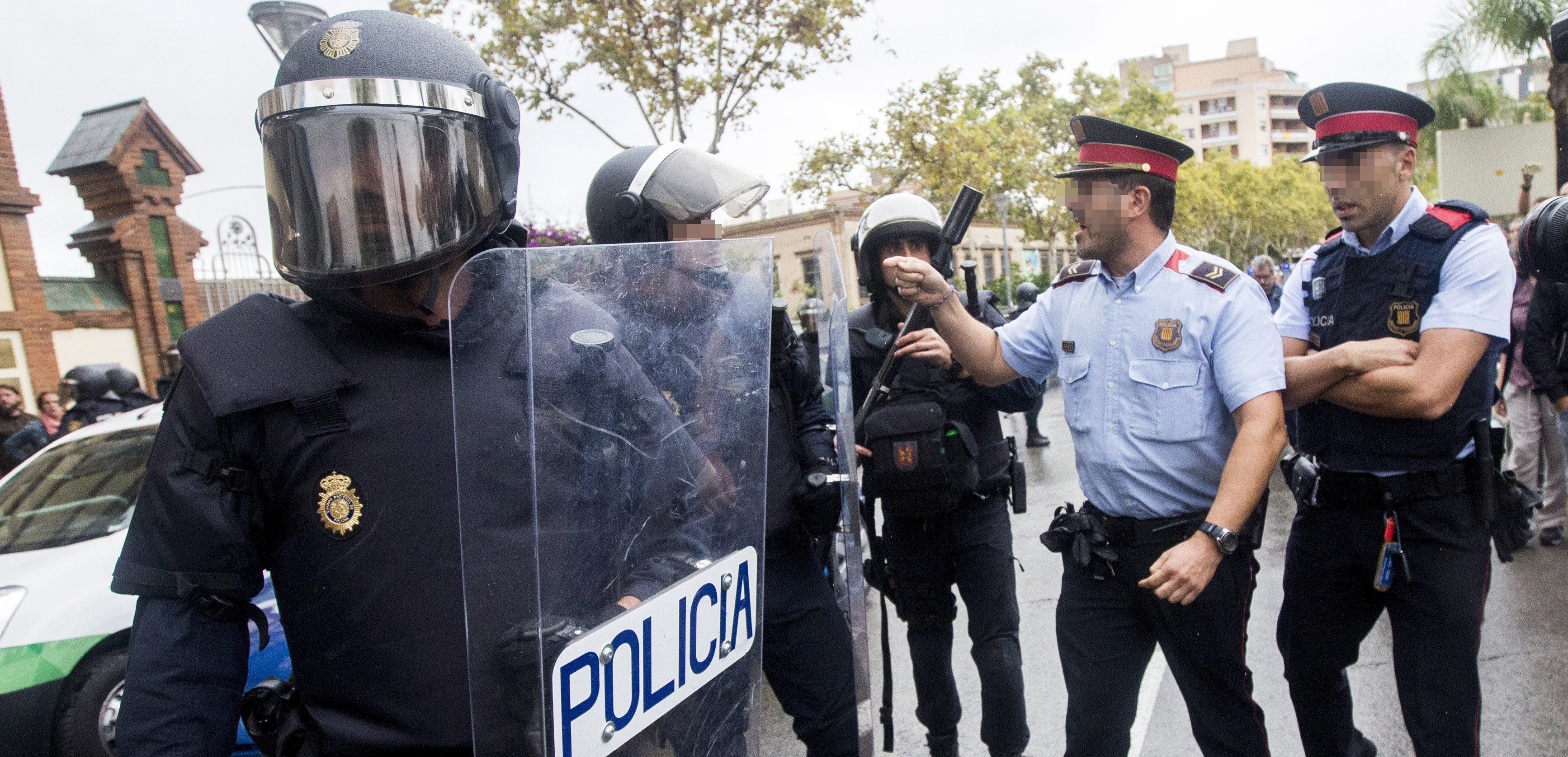 Agentes antidisturbios de la Policía Nacional y de los Mossos d' Esquadra discuten frente al Instituto Can Vilumara de L'Hospitalet de Llobregat, el pasado domingo