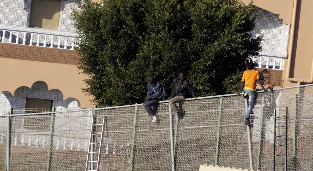Tres inmigrantes se encaramaban en la zona alta de la valla de Melilla, para intentar entrar en España. 
