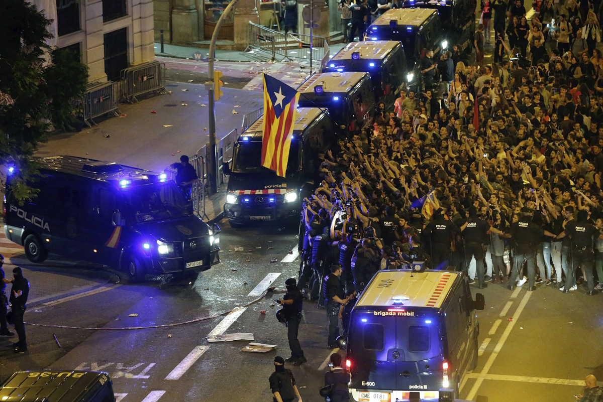 Miembros de los Mossos de Escuadra escoltan la salida de varias furgonetas de la Policia Nacional de la jefatura Superior de Policia de Barcelona este lunes