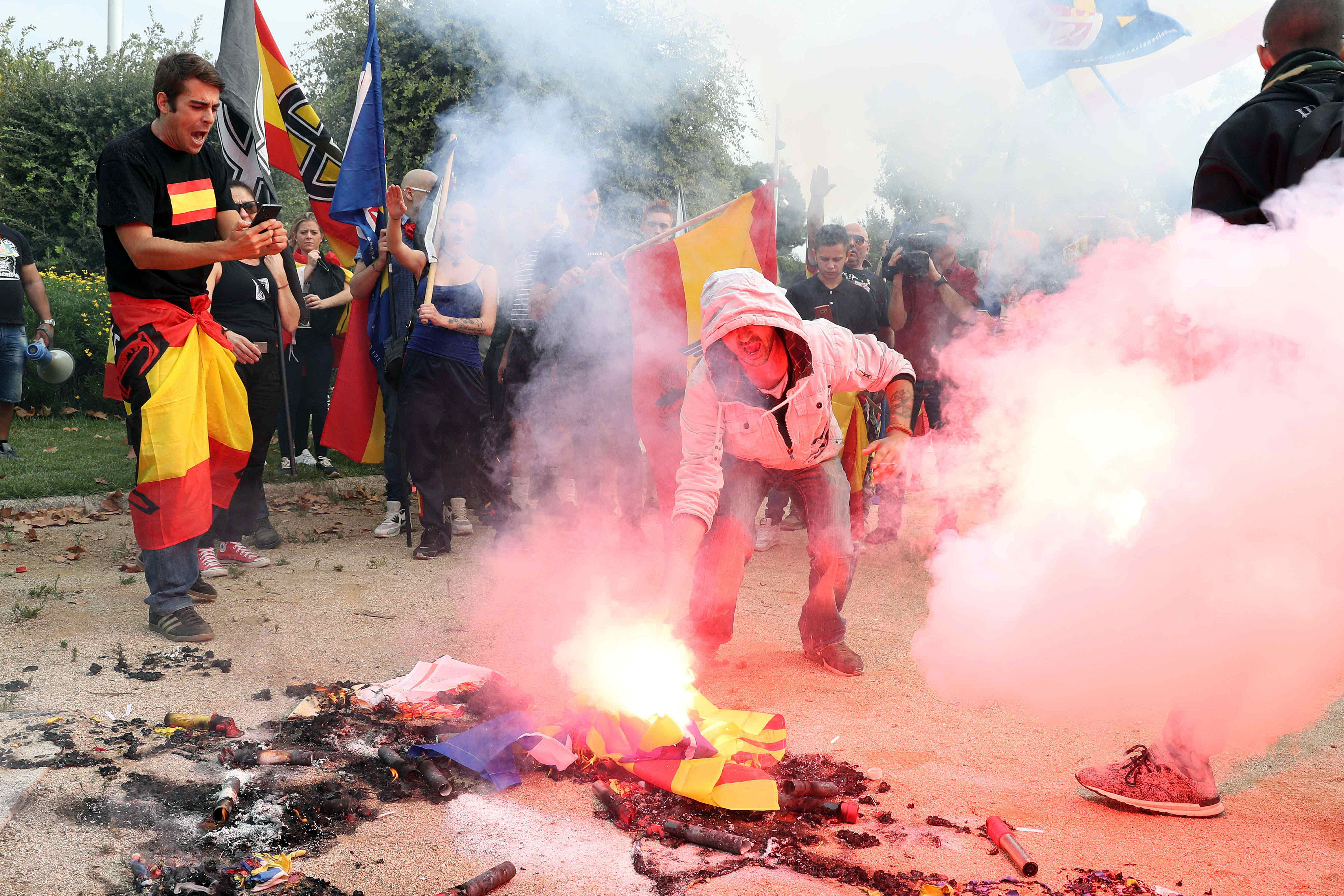 Fotografía de una manifestación de colectivos de ultraderecha portan banderas preconstitucionales mientras queman banderas esteladas