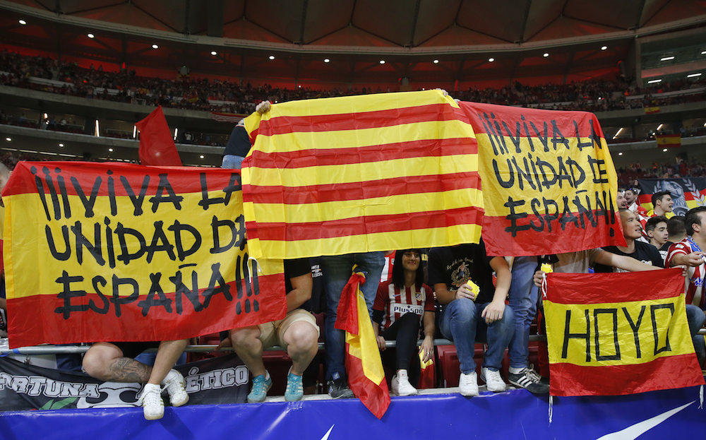 Varios aficionados portan banderas de España y Ctaluña antes del comienzo del encuentro de la octava jornada de Liga de Primera División entre el Atlético de Madrid y el FC Barcelona, en el estadio Wanda Metropolitano. 