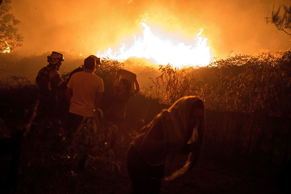 En la imagen, unos vecinos observan como se acerca a sus casas el incendio forestal de Carballeda de Avia (Ourense).