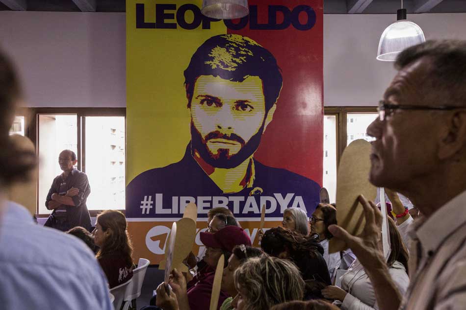 Un grupo de personas con afiches alusivos a leopoldo López y Antonio Ledezma asisten a una rueda de prensa de los partidos políticos Voluntad Popular y Alianza Bravo Pueblo en Caracas.