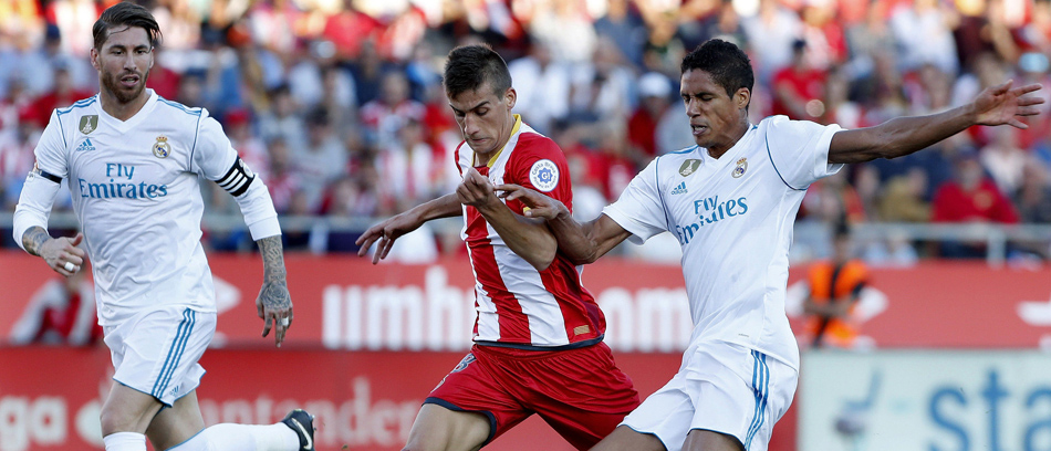 El centrocampista del Girona Pere Pons (c) disputa un balón con los defensas del Real Madrid Sergio Ramos (i) y Raphael Varane (d) durante el partido correspondiente a la décima jornada de LaLiga Santander disputado  en el Montilivi