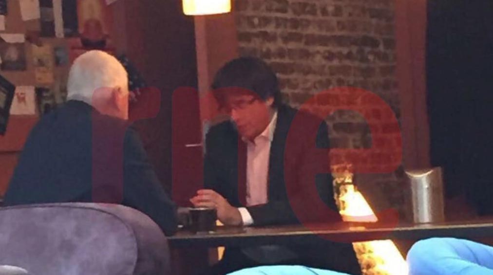 Imagen difundida por RNE en la que se ve a Puigdemont en una cafetería de Bruselas al mismo tiempo que su antiguo gobierno llegaba a la Audiencia Nacional.