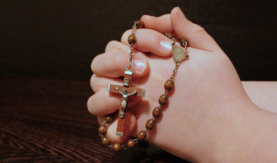Una fiel sostiene un rosario mientras reza.