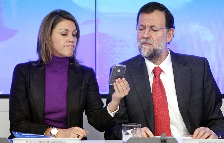 María Dolores de Cospedal y Mariano Rajoy observan un teléfono móvil