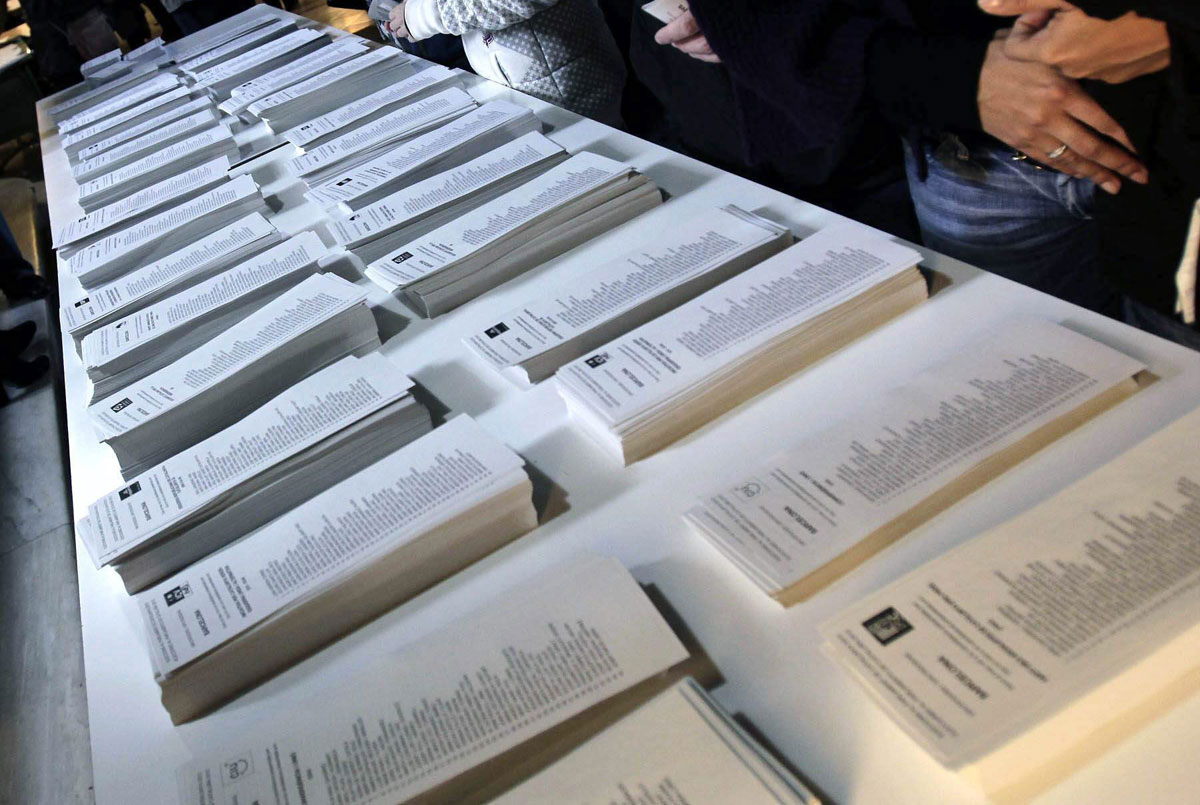 Varias personas observan las listas para ejercer su derecho al voto en un colegio de Barcelona