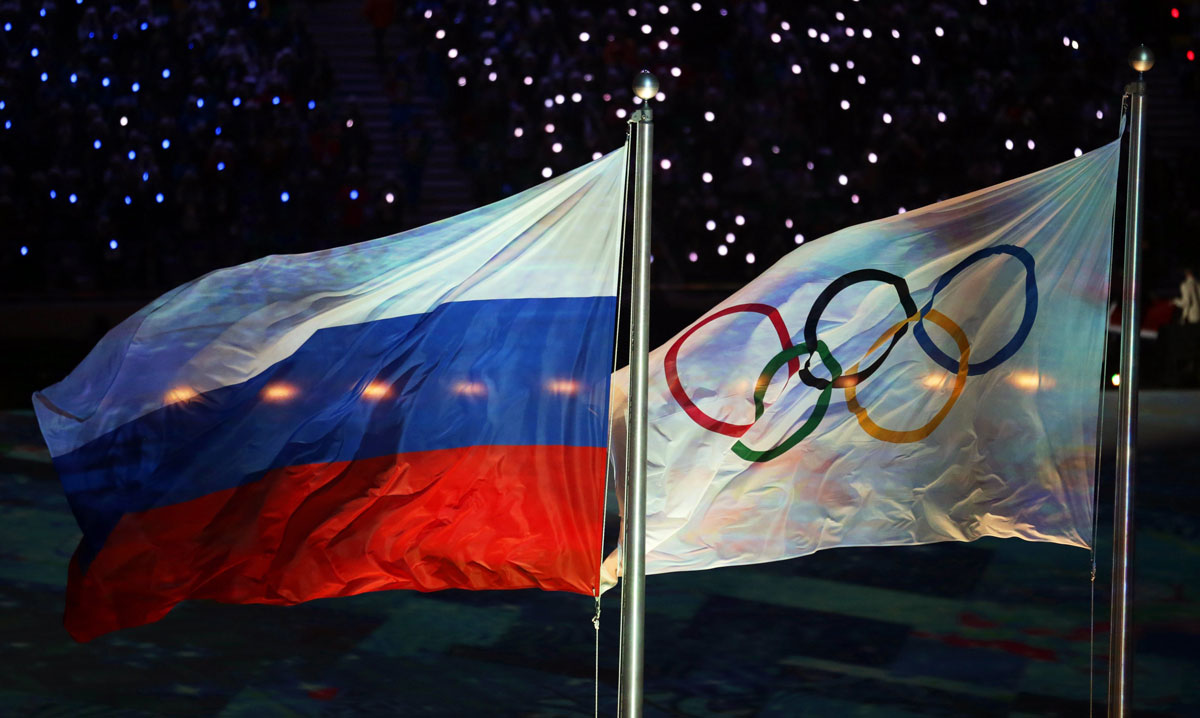 La bandera Olímpica (d), y la rusa (i), ondean durante la ceremonia de clausura de los Juegos Olímpicos de Invierno de Sochi 2014
