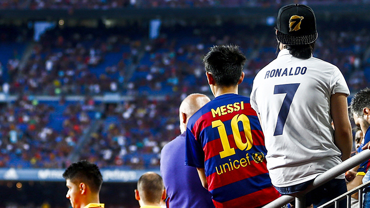 Dos espectadores de fútbol con las camisetas de Messi y Ronaldo