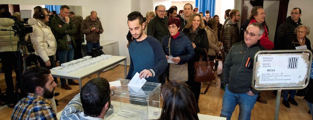 Un ciudadano deposita su voto en una urna en el colegio electoral de Sant Julià de Ramis, en Barcelona.