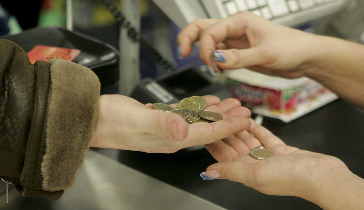 Una cajera ayuda a un cliente a contar las monedas de euro