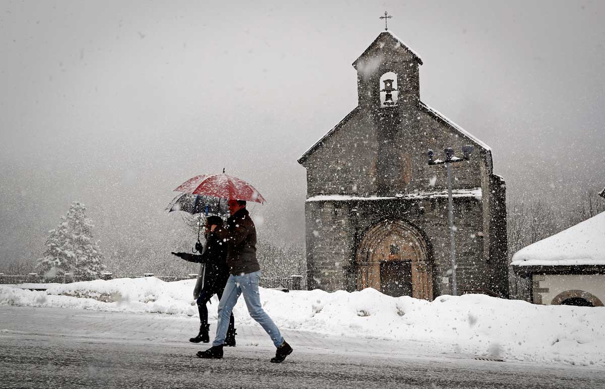 Dos personas caminan bajo una intensa nevada en Roncesvalles (Navarra) este mes de enero. EFE/Archivo