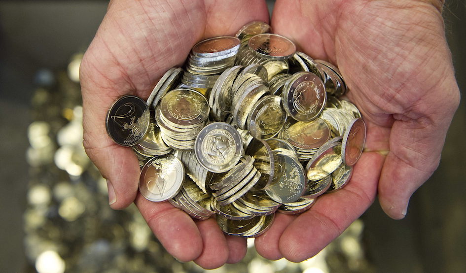 Un hombre sostiene varias monedas de euro. 