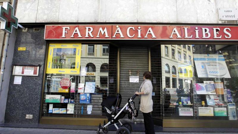 Una mujer contempla la fachada de una farmacia.