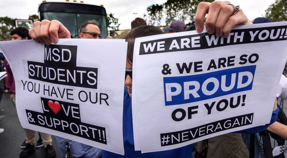 Estudiantes del instituto Marjory Stoneman Douglas reparten carteles mientras esperan al autobús en Parkland, Florida, Estados Unidos. 