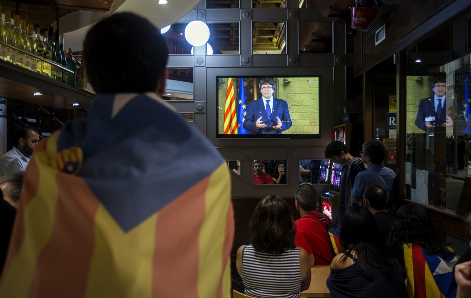 Un hombre con la estelada sigue en la televisión una comparecencia de Puigdemont.  Un hombre con la estelada sigue en la televisión una comparecencia de Puigdemont.