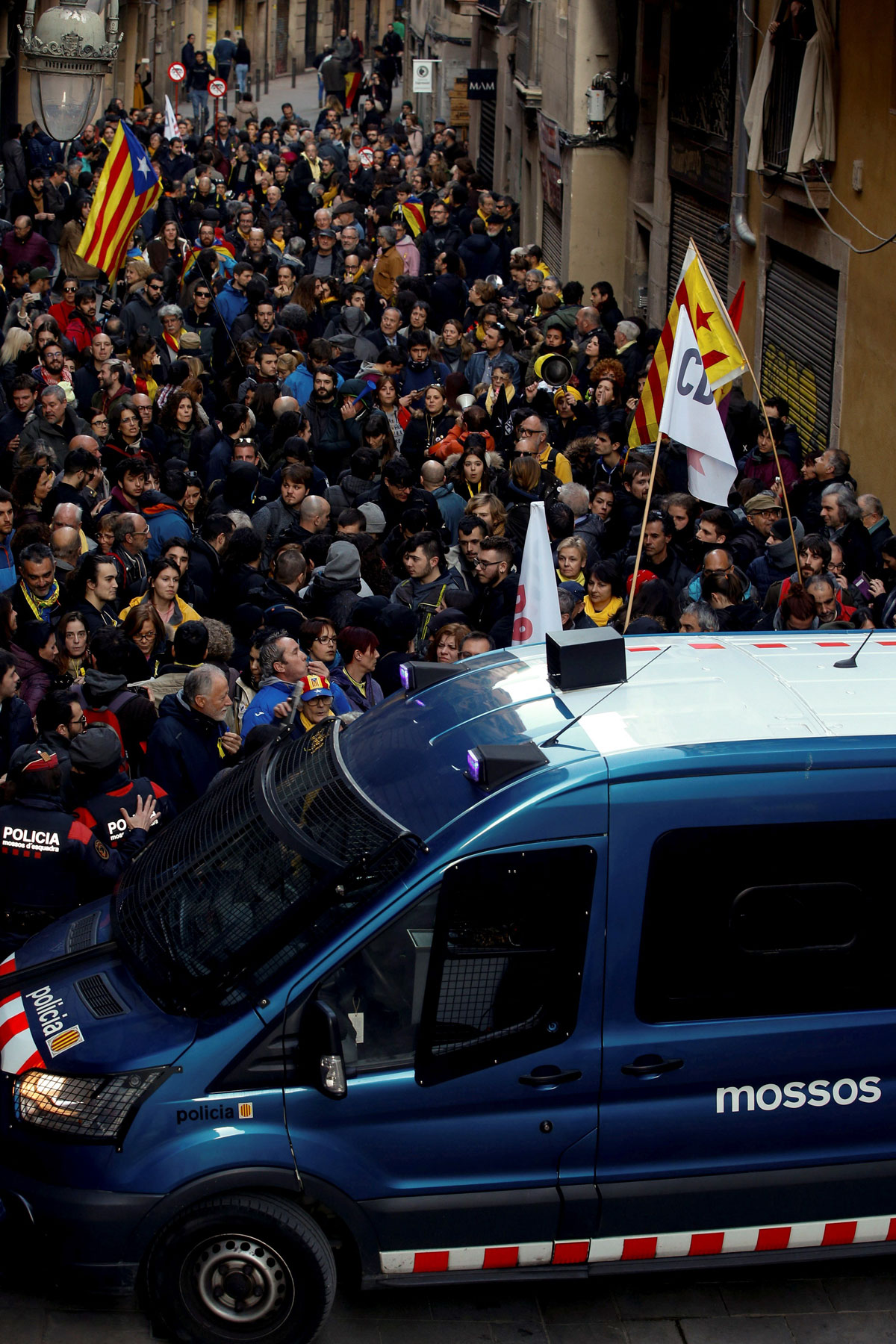 Miembros de los Mossos d'Esquadra vigilan a los manifestantes concentrados en los alrededores del Palau de la Música, contrarios a la presencia del Rey Felipe VI en la cena de bienvenida del Mobile World Congress (MWC), que se celebra en la ciudad Condal.