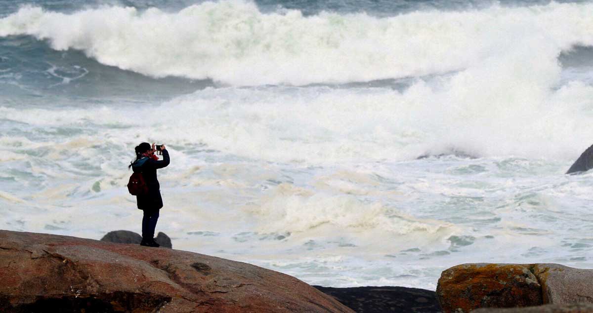 Una mujer observa el oleaje en Muxía (A Coruña). 