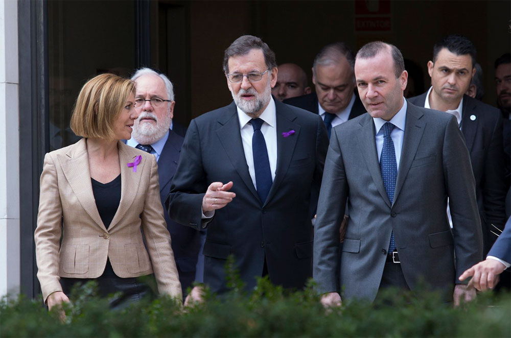 El presidente del Gobierno, Mariano Rajoy, junto a la ministra de Defensa, María Dolores de Cospedal, ambos con lazo morado, y el líder de los 'populares europeos